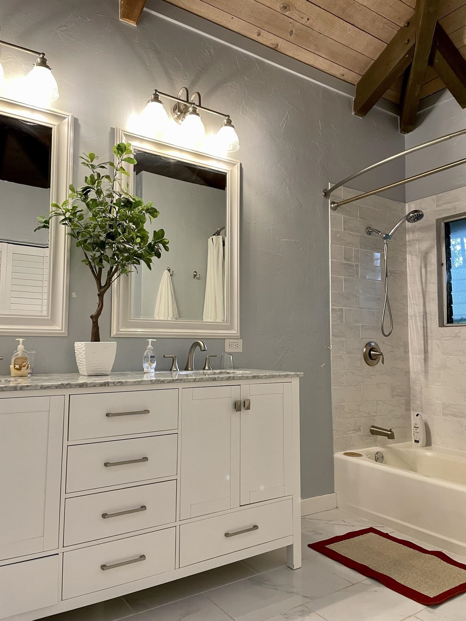 620 Awalau Road Haiku, HI 96708 - Photo 17 of 50 a bathroom with a double vanity sink a mirror a bathtub and shower