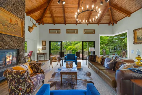 a living room with furniture a fireplace and floor to ceiling windows