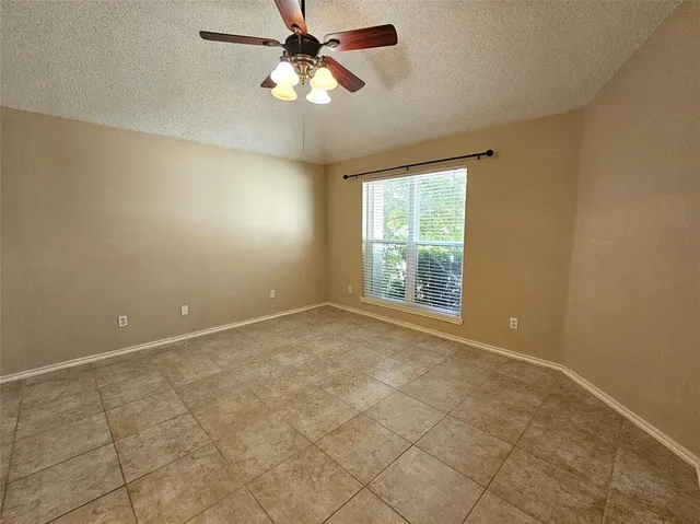 an empty room with windows and fan