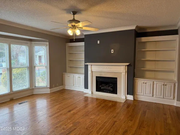 an empty room with wooden floor fireplace and windows