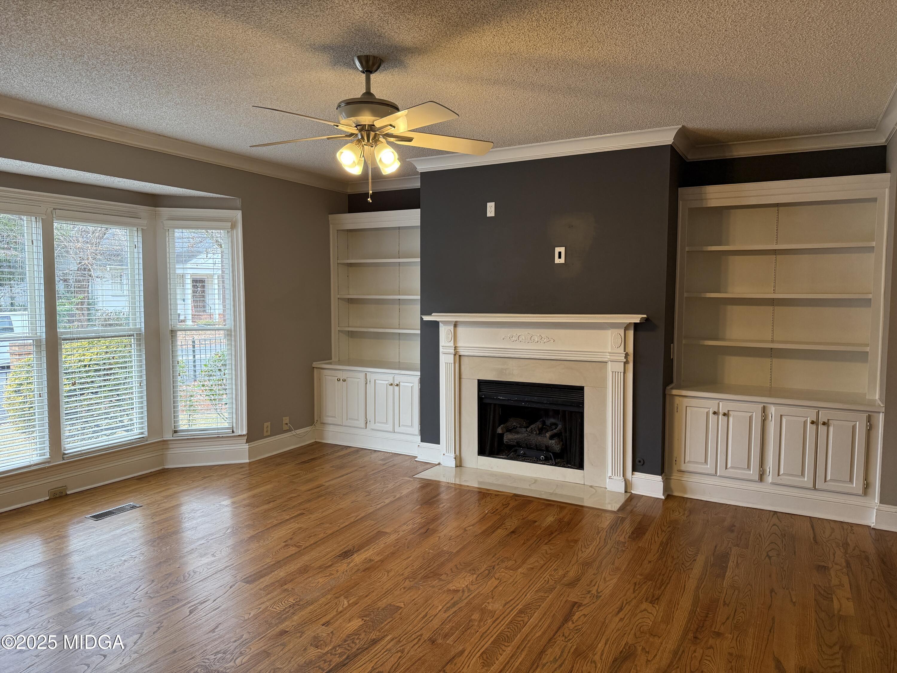 175 Corbin Avenue, Unit A Macon, GA 31204 - Photo 2 of 15 an empty room with wooden floor fireplace and windows