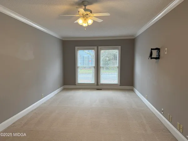 an empty room with windows and chandelier fan