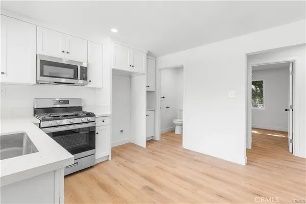 a kitchen with stainless steel appliances a stove a microwave and a hard wood floors