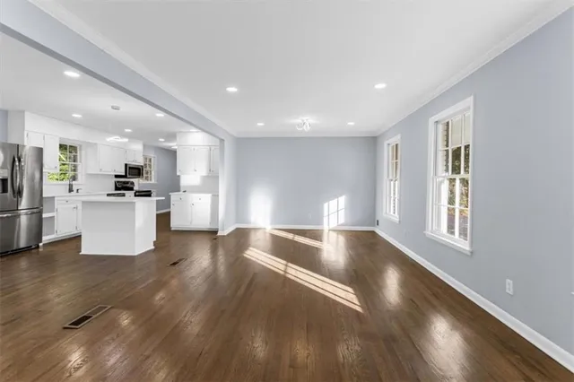 a view of an empty room with a window and wooden floor