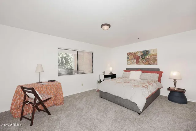 a spacious bedroom with a bed a table and chair