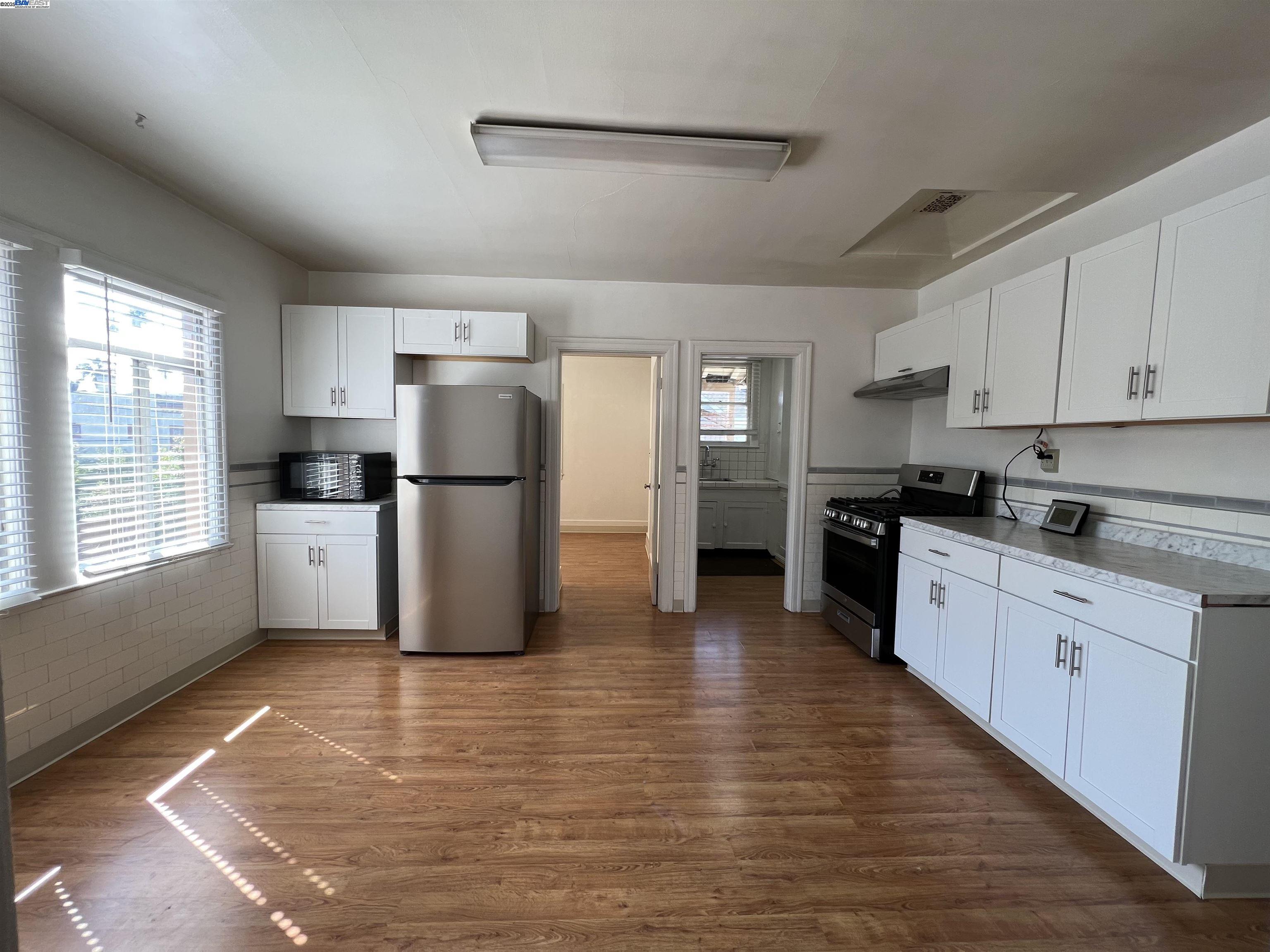 1301 9th Street Alameda, CA 94501 - Photo 11 of 12 a kitchen with stainless steel appliances granite countertop a refrigerator sink and cabinets