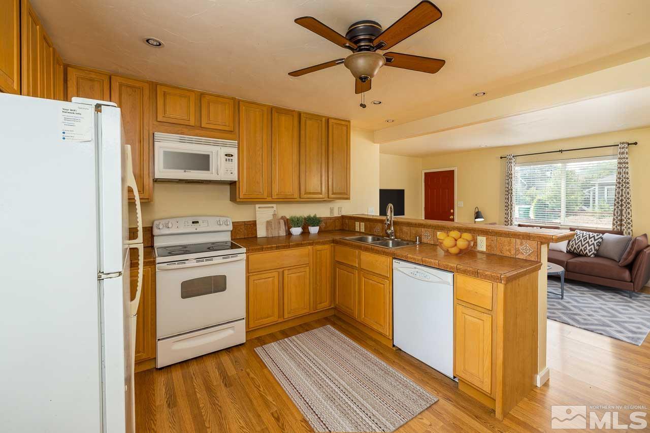 120 Caliente Street Reno, NV 89509 - Photo 3 of 20 a kitchen with stainless steel appliances granite countertop a stove a sink dishwasher a refrigerator and a oven with wooden floor