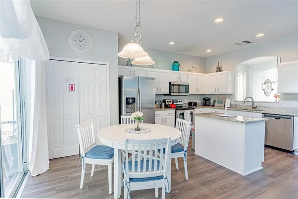 a kitchen with kitchen island granite countertop a sink a counter top space stainless steel appliances and a large window