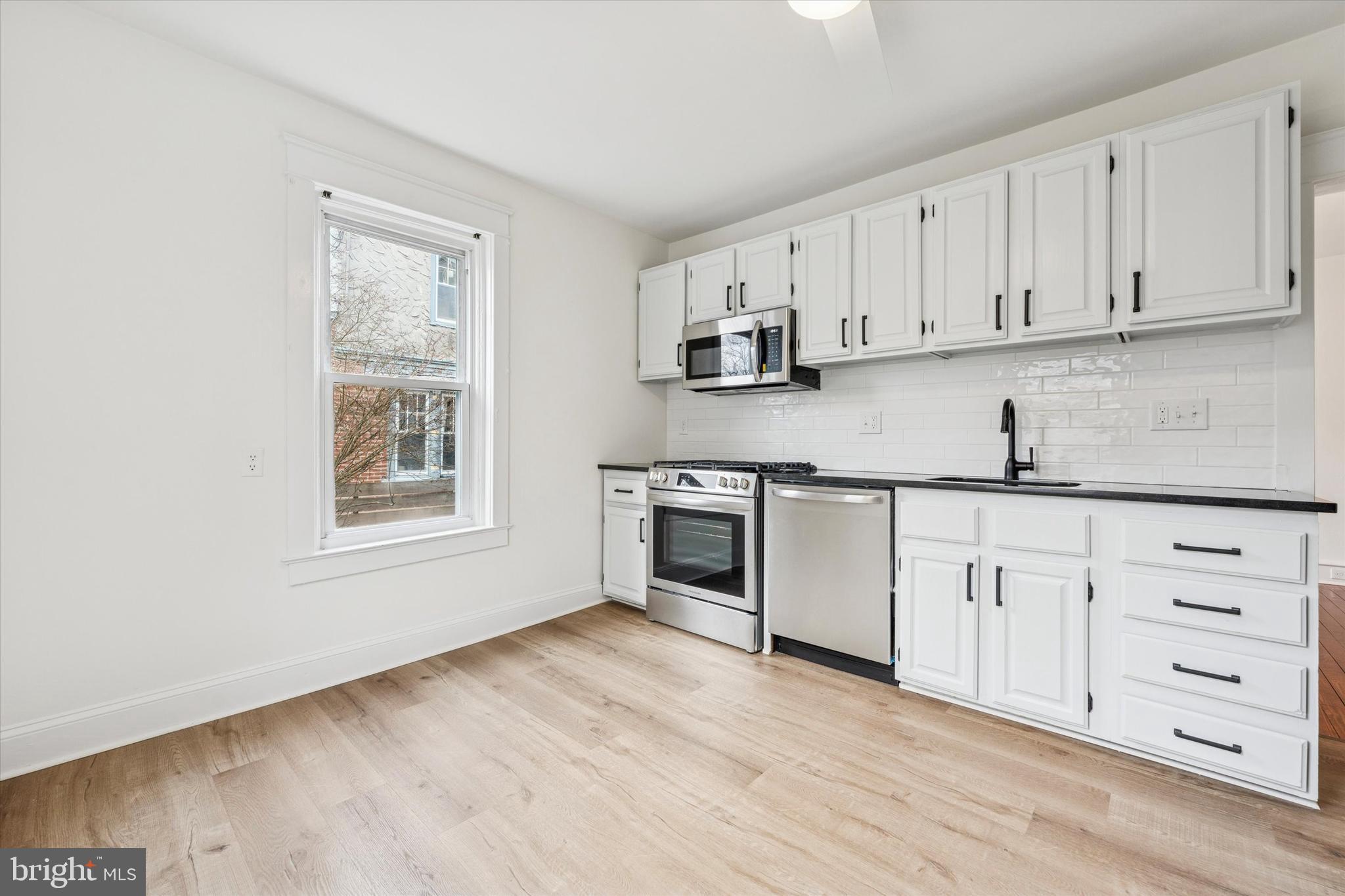 10 West Jefferson Street Media, PA 19063 - Photo 12 of 24 a kitchen with granite countertop white cabinets and stainless steel appliances