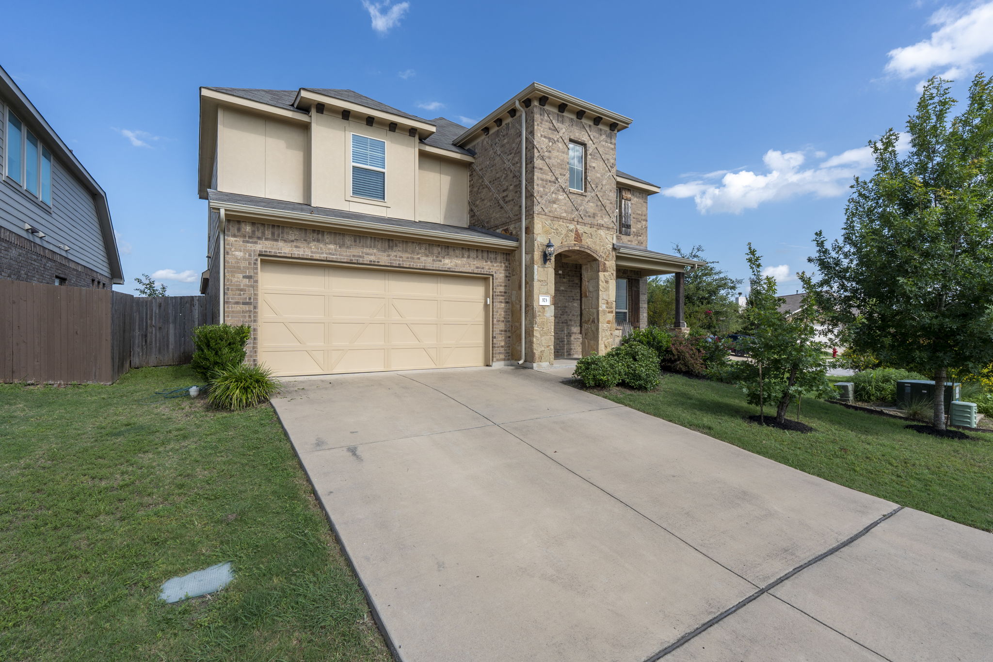 373 Rough Bark Street Buda, TX 78610 - Photo 35 of 39 A welcoming facade with a classic brick and stone exterior, featuring an integrated garage and covered entry.
