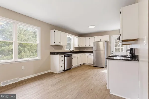 a kitchen with a refrigerator a stove top oven and white cabinets