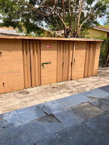 a view of a refrigerator in kitchen and an empty room with wooden floor