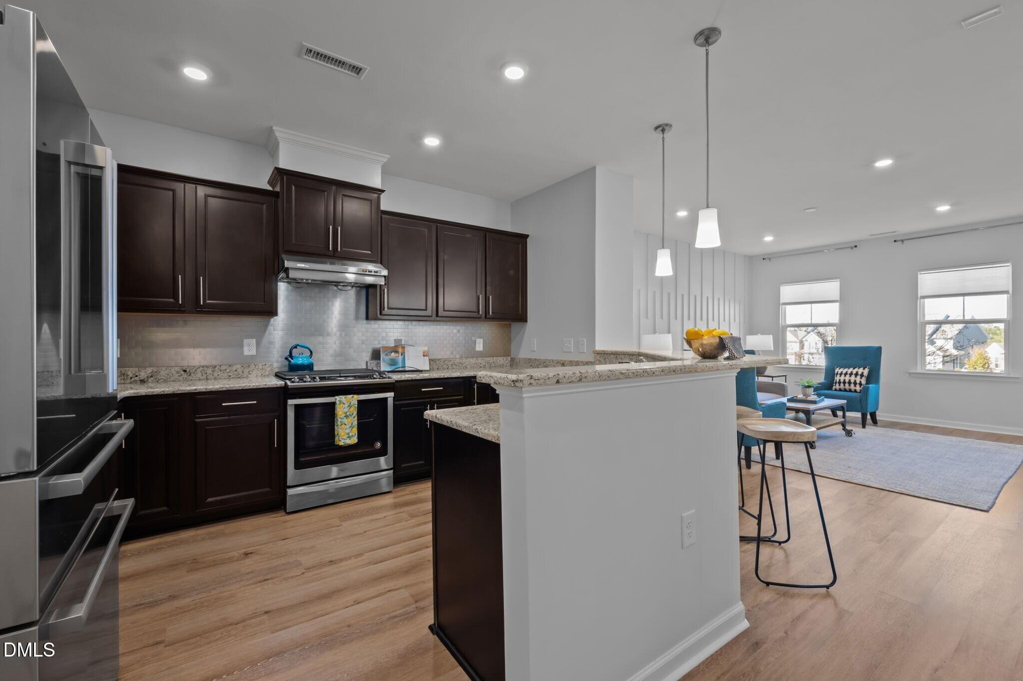 17 Rambler Lane Morrisville, NC 27560 - Photo 12 of 50 a kitchen with a refrigerator a stove top oven a sink dishwasher and white cabinets with wooden floor
