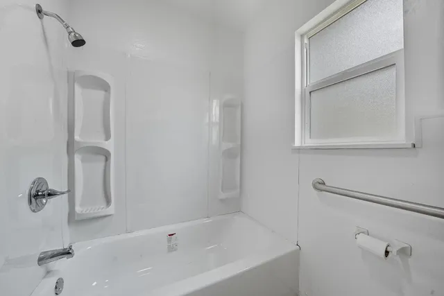 a white bath tub sitting next to a white sink and vanity