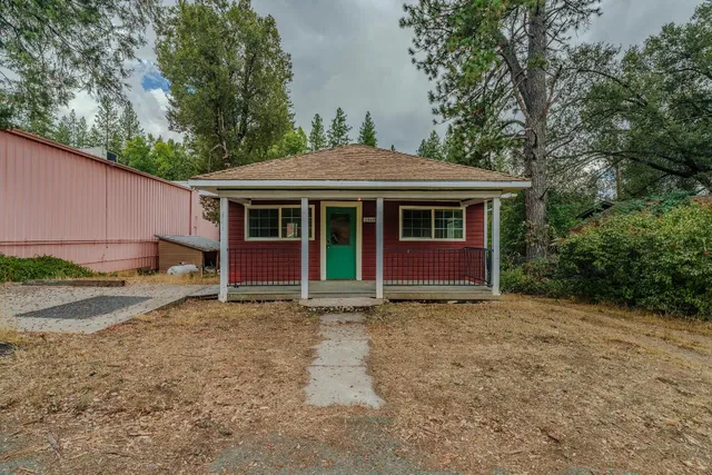 a view of a house with a yard and large tree