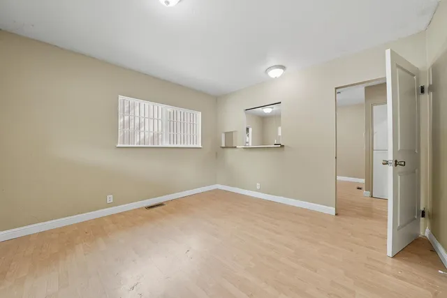 a view of empty room with wooden floor and window