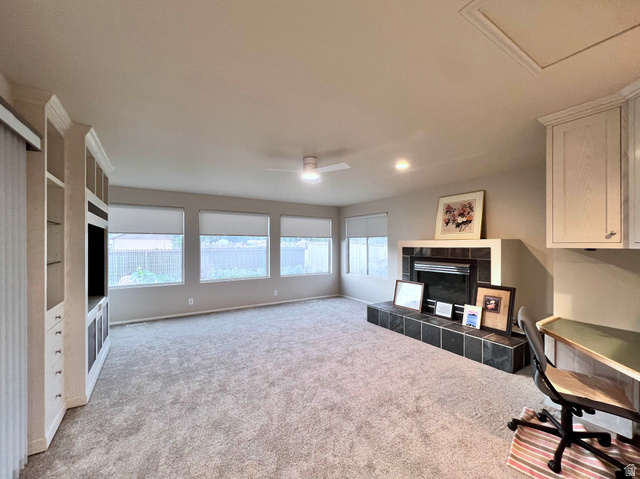 8097 South 535 East Sandy, UT 84070 - Photo 6 of 15 Spacious room featuring a built-in entertainment center, a fireplace with a tiled hearth and surround, a bank of four windows, a ceiling fan, and recessed lighting
