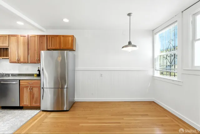 a kitchen with stainless steel appliances granite countertop a dining table chairs and a refrigerator