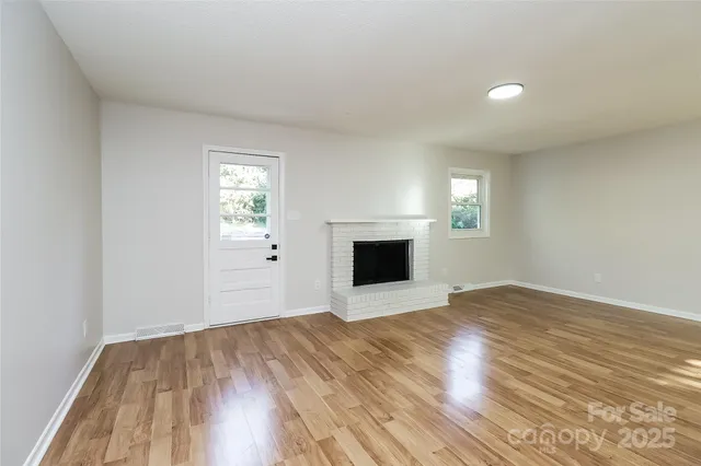 a view of empty room with wooden floor and fireplace