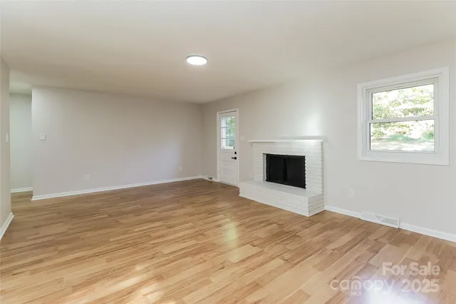 a view of empty room with wooden floor and fireplace