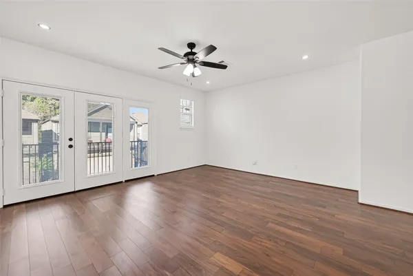 a view of an empty room with wooden floor and a ceiling fan