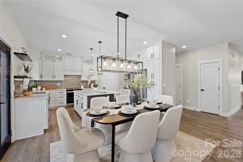a kitchen with stainless steel appliances granite countertop a sink a stove a dining table and chairs