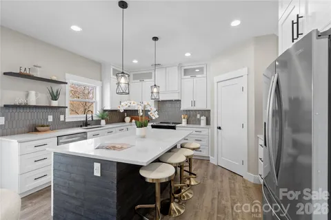 a kitchen that has a lot of white cabinets and stainless steel appliances