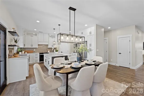 a kitchen that has a lot of white cabinets and stainless steel appliances