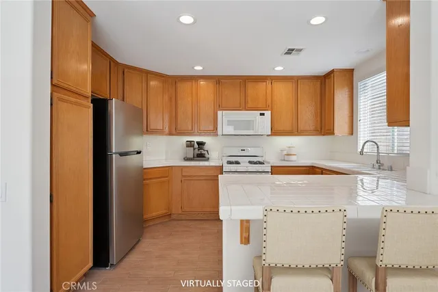 a kitchen with a refrigerator a stove a sink dishwasher and wooden cabinets with wooden floor