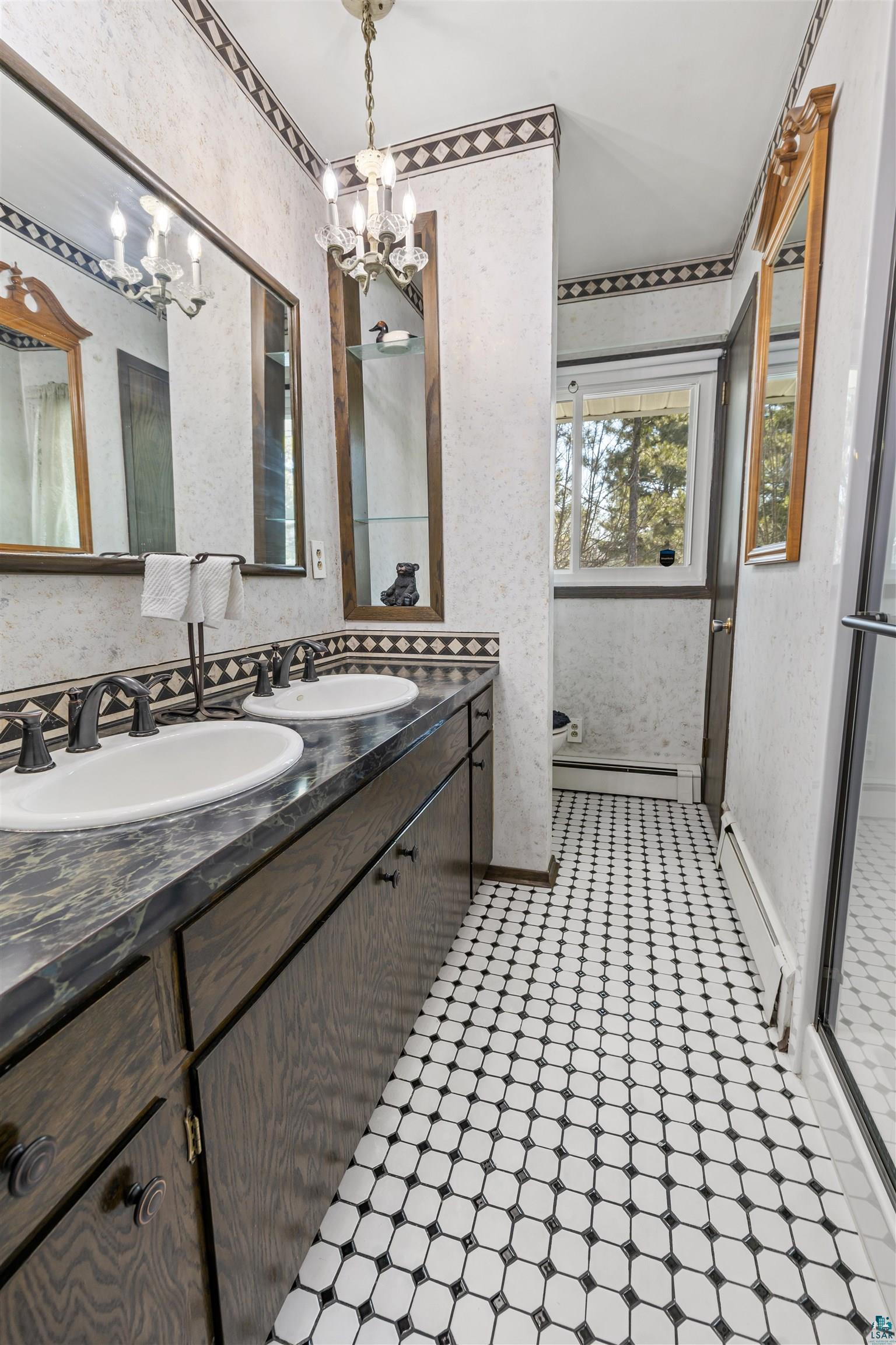 3975 Long Lake Shores Road Eveleth, MN 55734 - Photo 46 of 84 Bathroom featuring double vanity, a baseboard radiator, a chandelier, vaulted ceiling, and light flooring