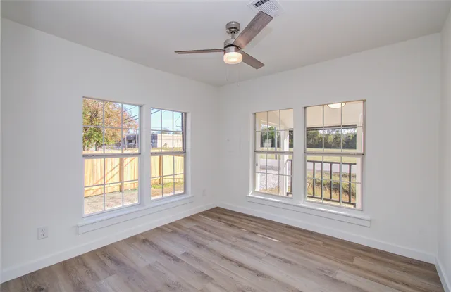 a view of an empty room with wooden floor and a window