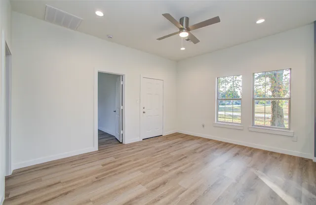 an empty room with wooden floor and windows