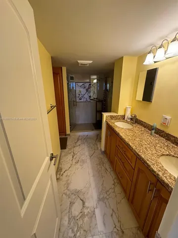 a bathroom with a granite countertop sink a mirror and a shower