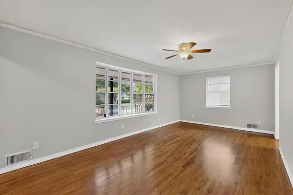 a view of an empty room with a window and wooden floor