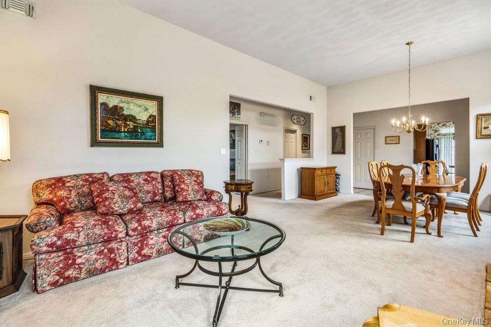 587 Leisure Drive Ridge, NY 11961 - Photo 11 of 49 a living room with furniture and a chandelier
