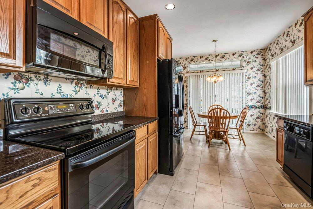 587 Leisure Drive Ridge, NY 11961 - Photo 25 of 49 a kitchen with stainless steel appliances granite countertop a stove top oven a sink and cabinets