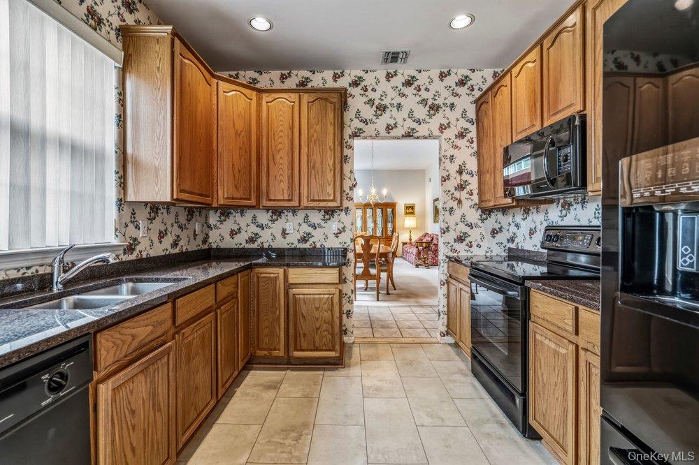 587 Leisure Drive Ridge, NY 11961 - Photo 32 of 49 a kitchen with stainless steel appliances granite countertop a stove a sink and a refrigerator