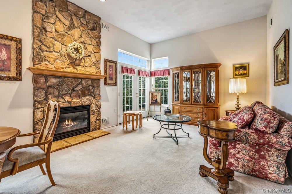 587 Leisure Drive Ridge, NY 11961 - Photo 9 of 49 a living room with furniture a fireplace and a floor to ceiling window