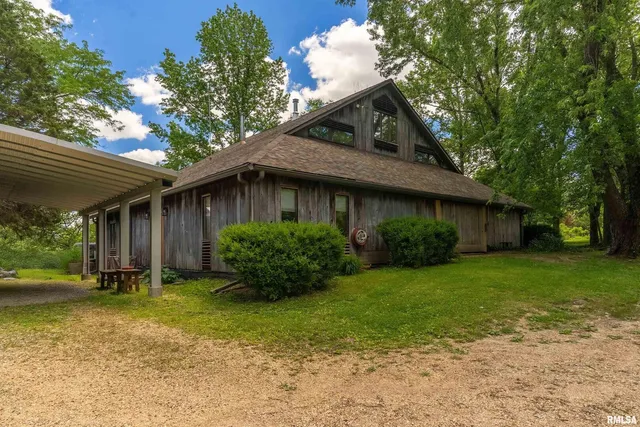 a view of a wooden house with a small yard plants and large tree