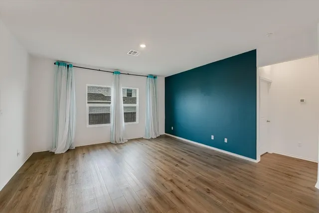 a view of an empty room with wooden floor and closet