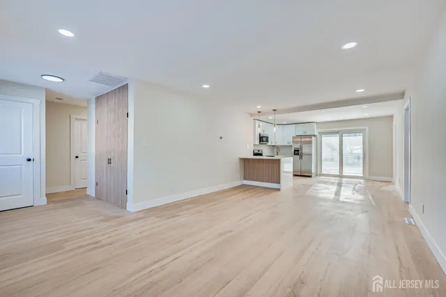 a view of kitchen and empty room with wooden floor