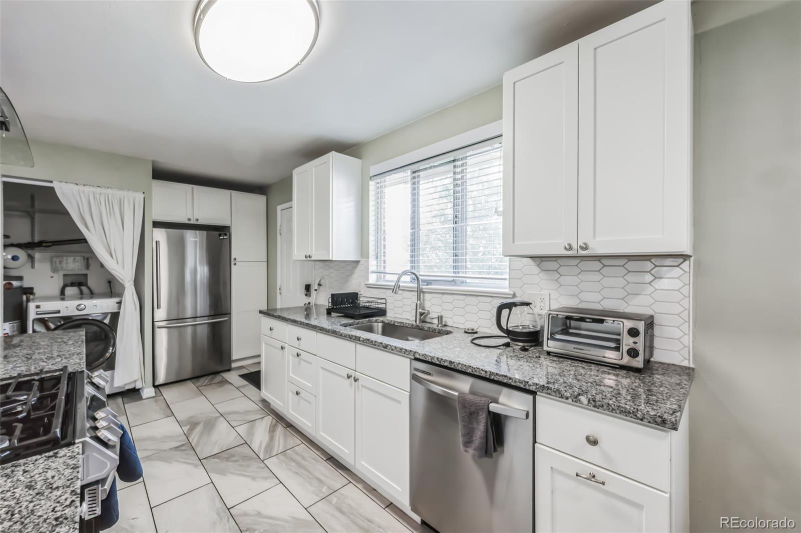 1070 South Decatur Street Denver, CO 80219 - Photo 12 of 18 a kitchen with stainless steel appliances granite countertop a sink stove and refrigerator