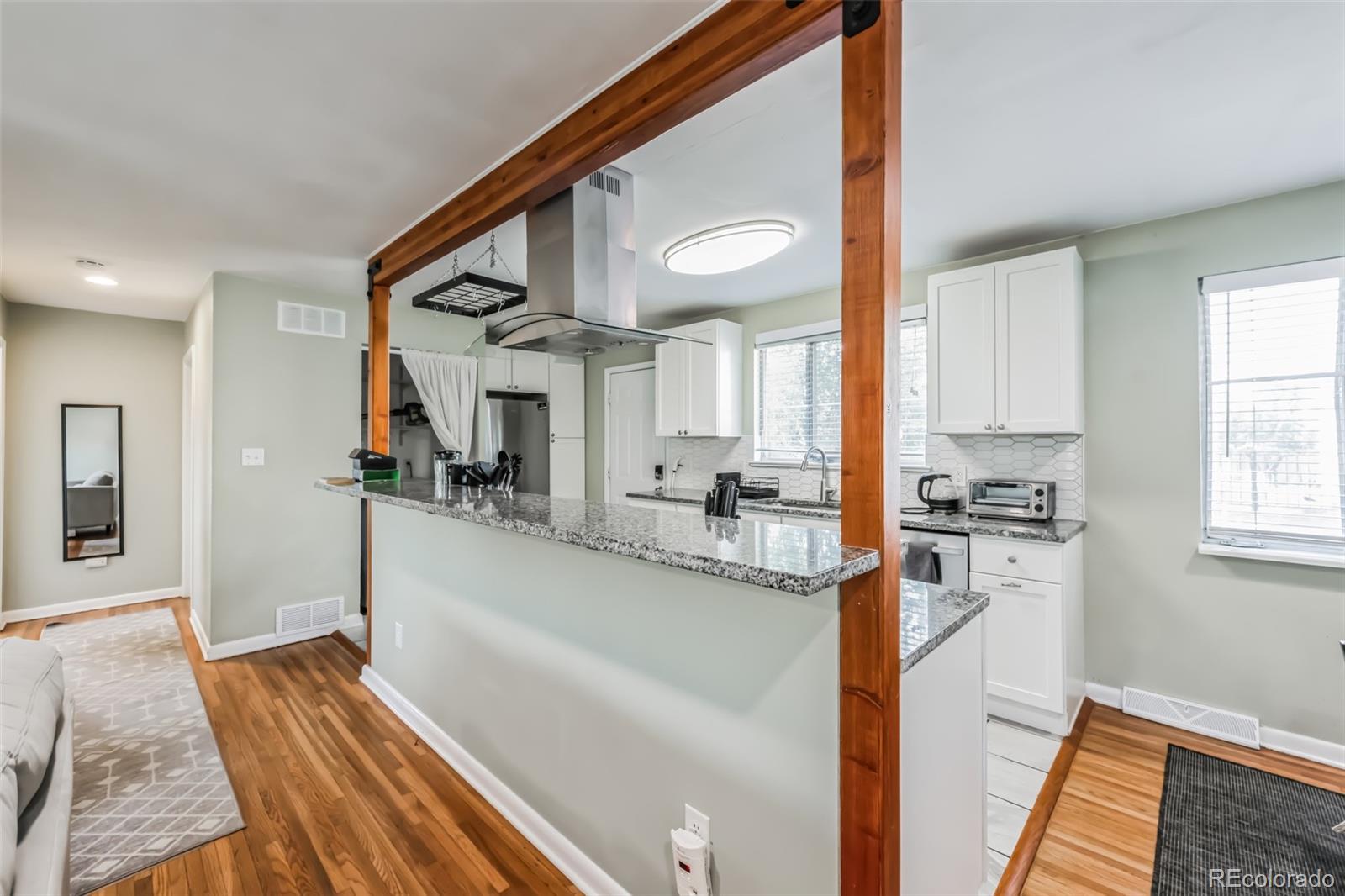1070 South Decatur Street Denver, CO 80219 - Photo 13 of 18 a kitchen with stainless steel appliances granite countertop a refrigerator a stove and a sink with wooden floor