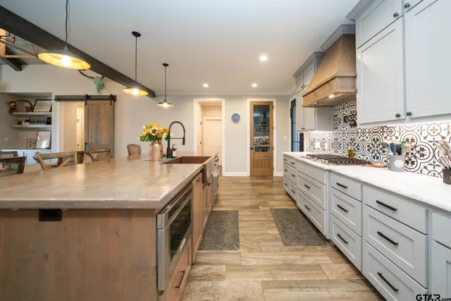 a kitchen with stainless steel appliances kitchen island granite countertop a table chairs and a refrigerator