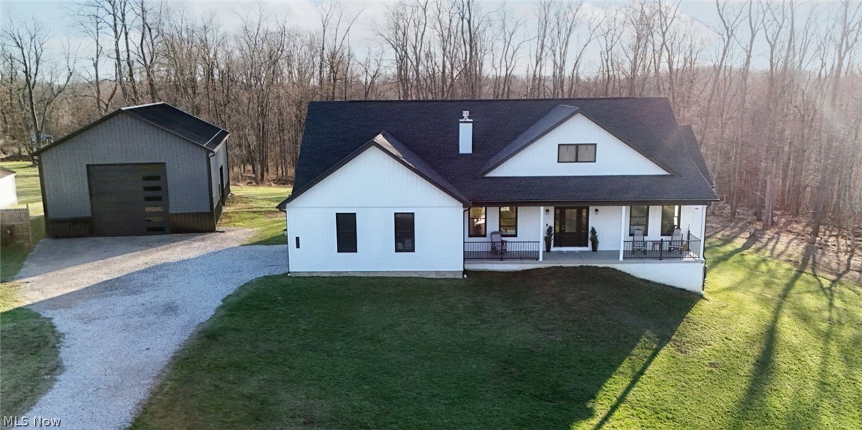 Front of home featuring a gravel driveway, a pole barn, a lawn, and covered porch