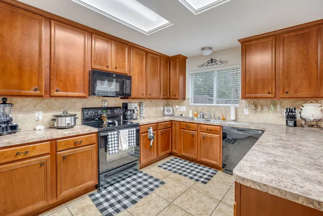 a kitchen with stainless steel appliances granite countertop a stove top oven a sink dishwasher and cabinets with wooden floor