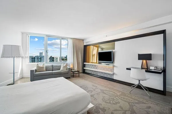 a spacious bedroom with a bed and a flat screen tv