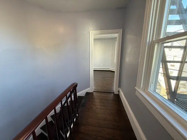 a view of a hallway with wooden floor and staircase