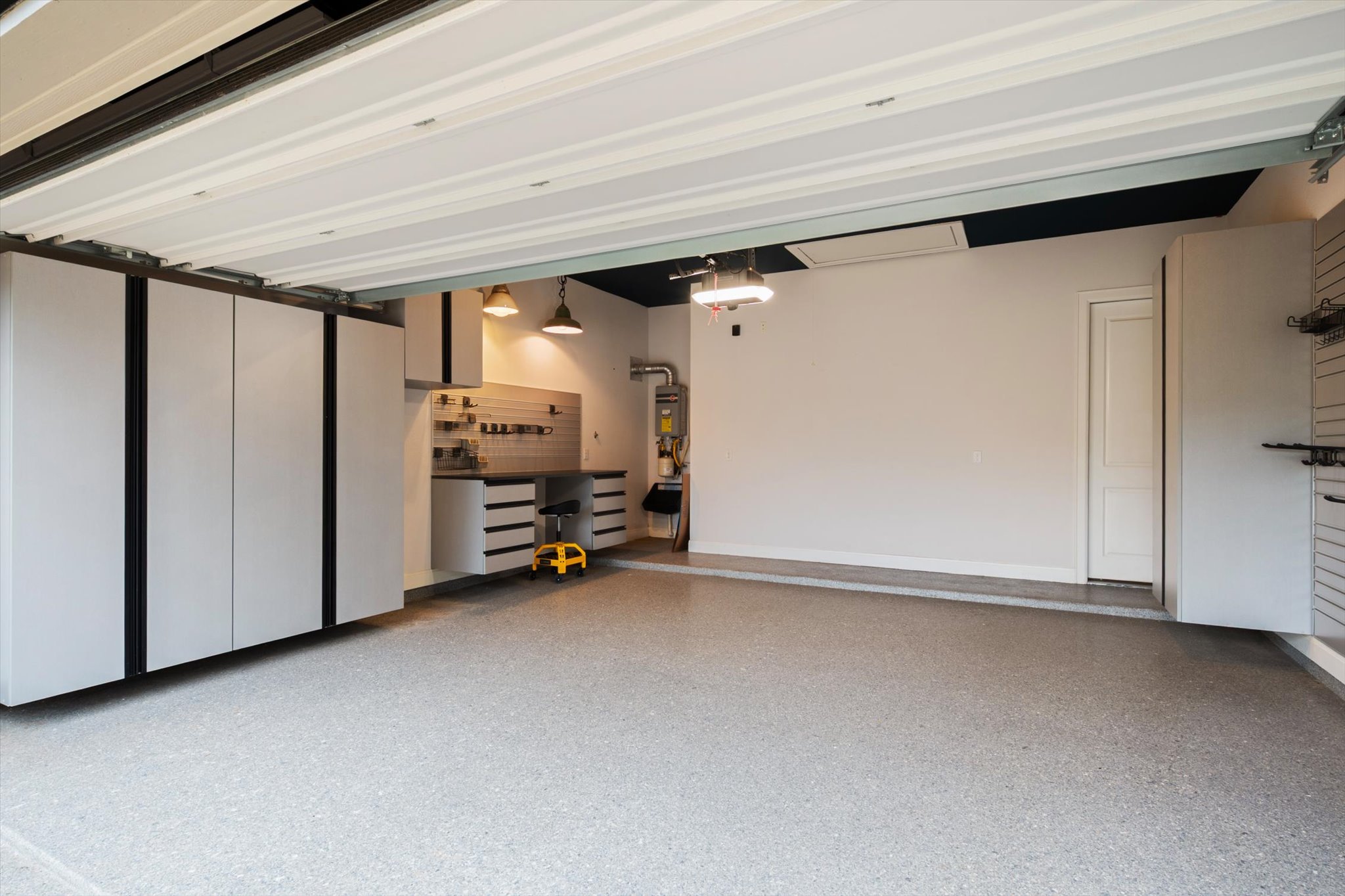 1401 Calago Cove Leander, TX 78641 - Photo 28 of 40 Spacious garage with epoxy flooring, extensive built-in cabinetry, a dedicated workbench area, wall-mounted storage tracks, and overhead lighting