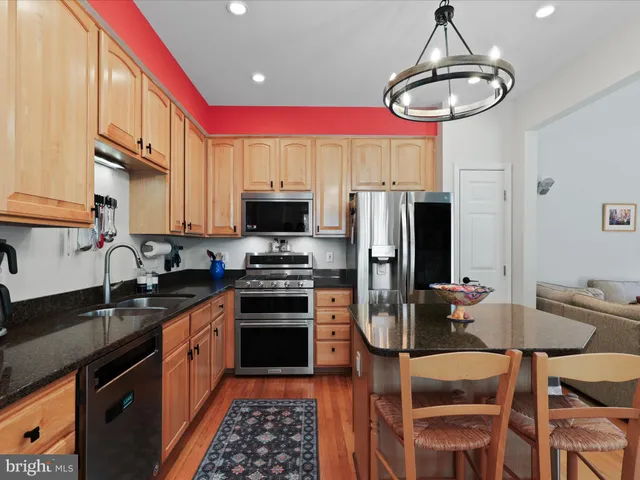 a kitchen with stainless steel appliances a stove a sink a microwave a refrigerator and chairs
